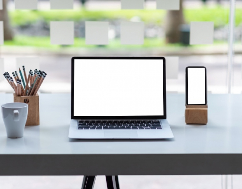 Front view laptop and mobile phone with a blank white screen with a coffee cup, a pencil placed on the desk at the office. Mock up.