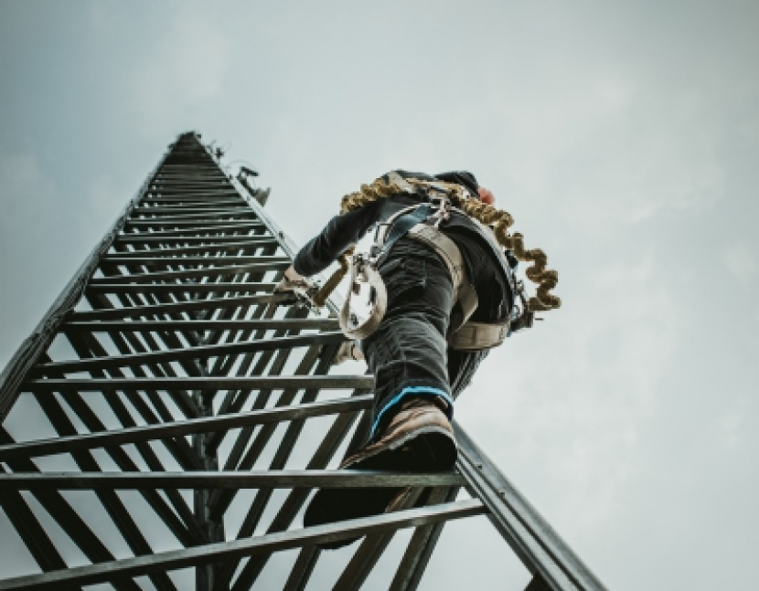 Telecom Worker Climbing Antenna Tower with Tools and Harness